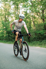 Fototapeta na wymiar A male cyclist in gear rides a road bike outside the city