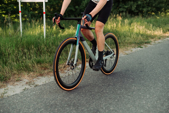 Close up photo. A man rides a road bike on a country road.