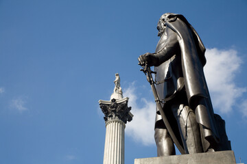 London - The statue of Major General Sir Henry Havelock  by  William Behnes (1856) and Admiral Nelson memorial from Trafalgar square in background - obrazy, fototapety, plakaty
