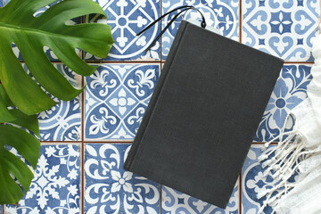 Blank book cover for mock up on mosaic tiles with tropical leaves for exotic travel vibe