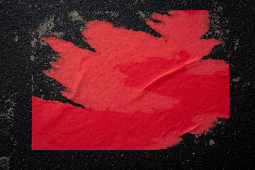 A piece of red paper on a black wall.