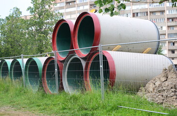 Large diameter pipes are stacked behind a mesh fence