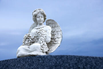 Fototapeta na wymiar Anges avec fruits dans les mains sur pierre tombale à l'heure bleue
