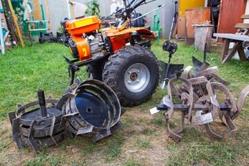 Obraz premium Agricultural walk-behind tractor with a set of attachments, hiller, milling cutters and lugs. Two-wheel tractor, industry