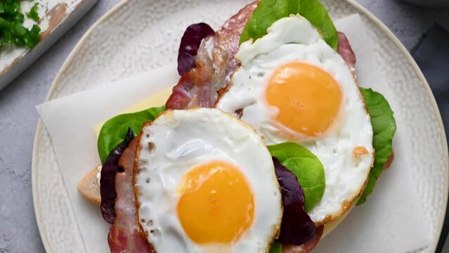 Breakfast food, fried eggs and bacon on toast served with cheese and fresh green salad leaves.