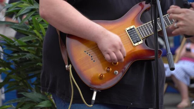 Guitarist playing a guitar riff on an electric guitar at a street music festival. Cover band performing at open air