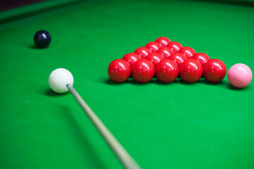 Snooker blls with snooker cue on a green table