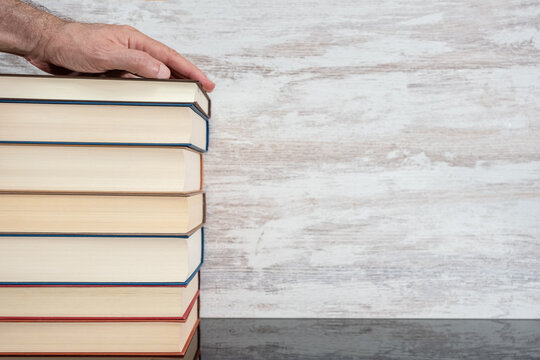 Hand on books stacked on a wooden table and background. Photo with copyspace.