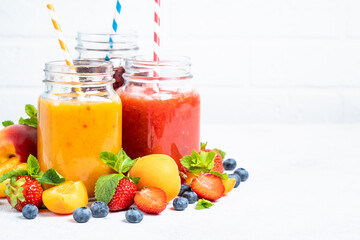 Smoothie with fresh fruits and berries at white background. Smoothie set in jars.