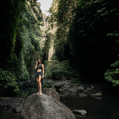 Naklejka na ściany i meble Woman stands on a stone in the jungle