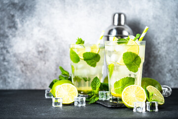 Mojito with rum, mint and lime on black background. Tradition Summer drink with shaker and bar utensils.