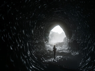 A person standing silouetted inside Katla Ice Cave, Mýrdalsjökull Glacier, South Iceland.