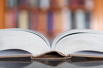 Large white book open on a glass table reflecting the image, photo with copyspace.