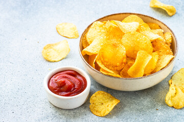 Potato chips in the bowl and ketchup sauce. Close up.