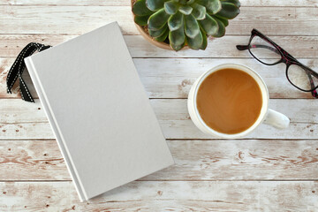 Blank book cover for mock up with coffee, plant and reading glasses.