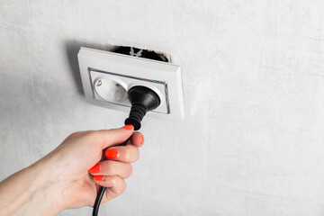The girl incorrectly removes the electric plug from the socket and breaks the socket. Danger of...