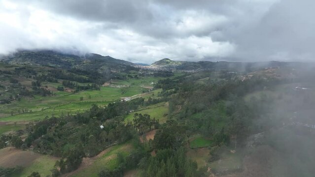Aerial view of the green field in the peruvian andes. Shot through the clouds with the city in the background. City of Cutervo, Cajamarca, Peru.