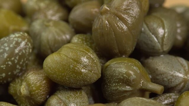 Pickled marinated capers rotate in macro. Ingredients for making spicy sauce, tartare or salad