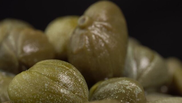Pickled marinated capers rotate on a black background. Ingredients for making spicy sauce, tartare or salad