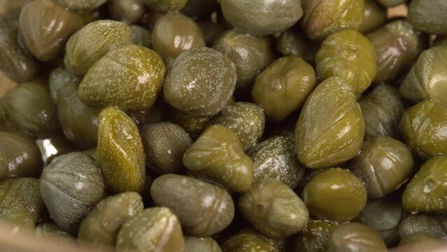 Pickled marinated capers rotate in macro. Ingredients for making spicy sauce, tartare or salad