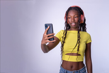 Mujer hermosa joven de color  que se hace un selfie con su teléfono con un fondo blanco. Chica...