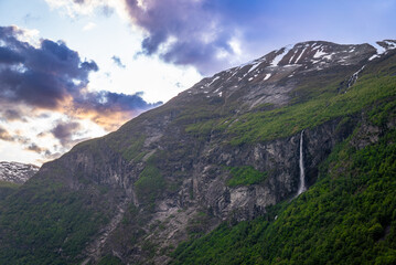 Fototapeta premium Dramatic colorful twilight summer sunset on the Geiranger fjord in Norway with vibrant clouds steep cliffs and waterfalls