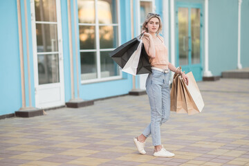 A young girl with bags in jeans leaves the store. Shopping.
