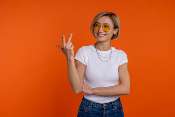 Smiling woman in white t shirt and jeans showing three fingers