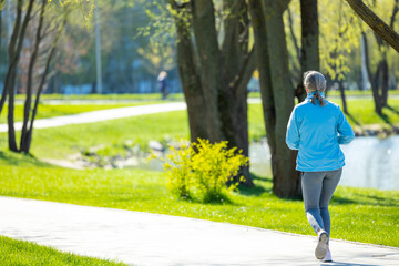 Woman in blue blazer running in th morning park