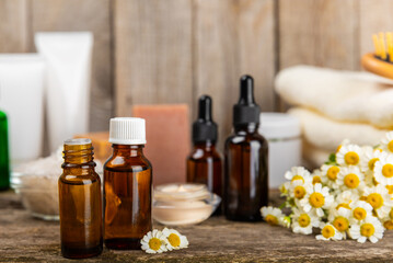 Chamomile Spa. Essential oil, sea salt, chamomile flowers, body cream and handmade soap. Natural herbal cosmetics with chamomile flowers on a textured background.Beauty concept. Cosmetic tube. 