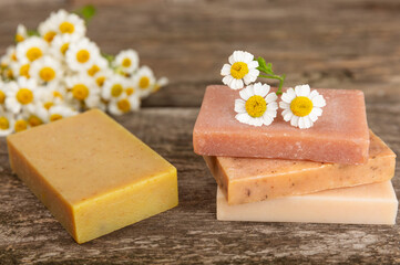 Natural homemade soap with chamomile flowers on vintage brown wood. Spa procedure. Beauty concept. Body skin care. Copy space. Place for text.