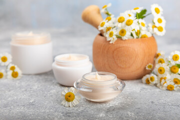 Fototapeta na wymiar Body and hand cream with chamomile flower on a concrete background. Herbal dermatological cosmetic hygiene cream. Natural cosmetic product. Cosmetic tube. Ecological cosmetics.Copy space.
