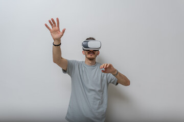 Futuristic man wearing virtual reality glasses interacts with the air in an isolated gray background.