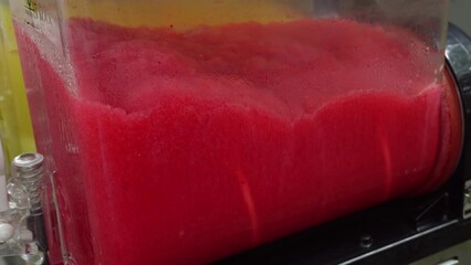 Machine making Ice Slushy Drinks. Tanks cooling and mixing beverage juice dispenser or juice cooler on counter on street food festival. Frozen drink Iced Juice Mixer. Juicer Containing Smoothie