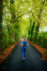 Young woman dressed in blue clothing walking along a path surrounded by vegetation