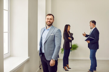 Portrait of happy smiling man looking at camera with realtor showing and discussing new apartment...