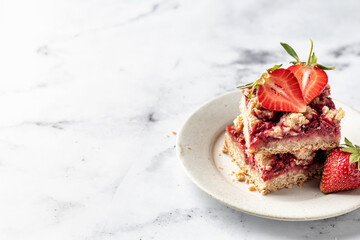 Two pieces of Strawberry granola bars on a pate on white marble background close up. Delisious...