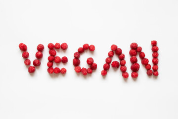 The word vegan is laid out from raspberries on a white background, no meat, no meat