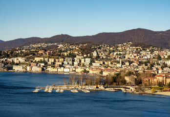 Fototapeta premium panorama in the morning of Lake Lugano, with the lake intensely blue in color, on its shore the city of Lugano, on the right a marina