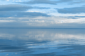 White blue clouds over lake, symmetric sky and water background, cloudscape on lake. Nature abstract, cloudy sky reflected on water, calm tranquil concept, aesthetic panoramic view