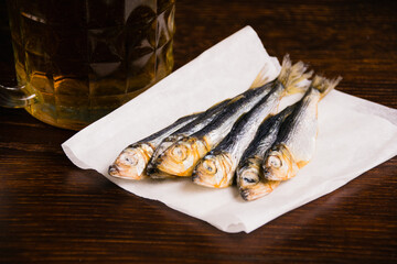 Delicious dried fish close-up on dark rustic wooden table and beer mug