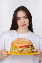 A woman is holding a big barbecue hamburger sandwich on the background. Fast food concept. The girl has a huge hamburger.