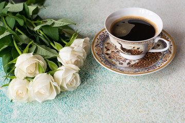 Fototapeta na wymiar A bouquet of white roses and a porcelain cup of aromatic coffee on a light background