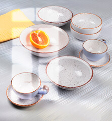 Ceramic bowls and cups are laid out on the table and illuminated by the light from the window.