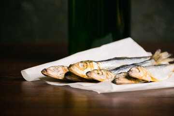 Tasty beer snack salted dried fish and cold beer in a glass bottle on a dark background