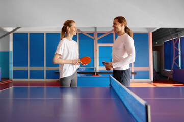 Male and female table tennis player taking break in ping pong practice