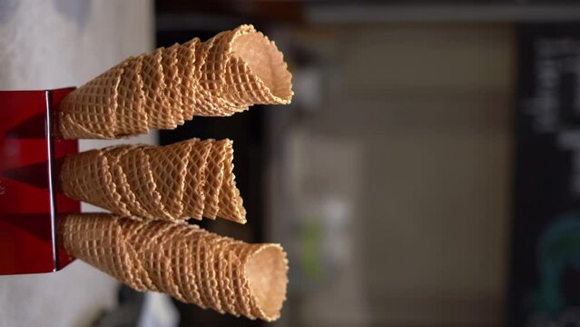 Choosing cone from pile of waffle cones for ice cream ready to be filled with ice cream in a cafe, restaurant. Showcase of a cafe or restaurant.