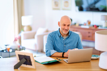 Confident mid aged man using notebook and working at home