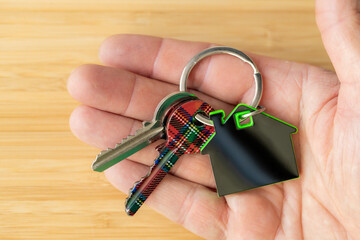 Apartment keys and house shaped keychain held in hand, Housing concept, dream home, mortgage loan,...