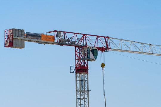 Red white painted tower crane in front of blue sky